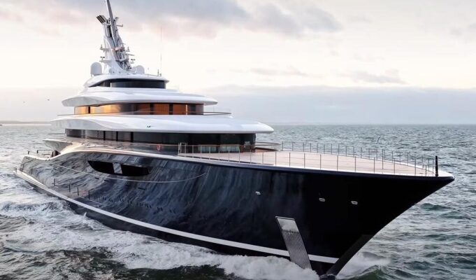 Travel Experts Reveal Amazing Benefits of Upholstery for Boat Interiors Large luxury motor yacht with a dark hull cruises the open sea at sunset, multi-deck white superstructure visible.