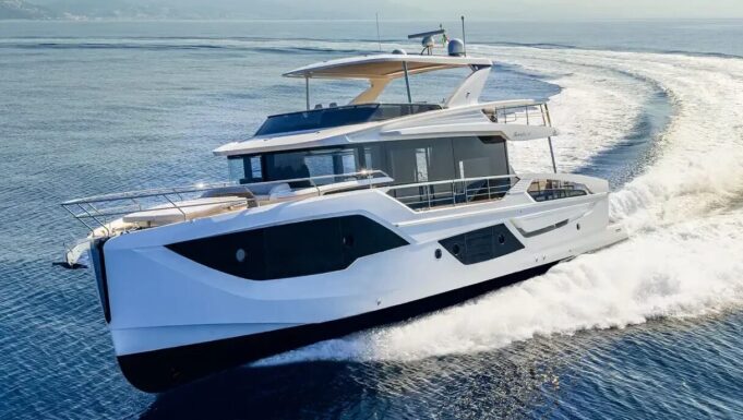 White luxury motor yacht cruising at speed through blue water, creating a white wake behind it.